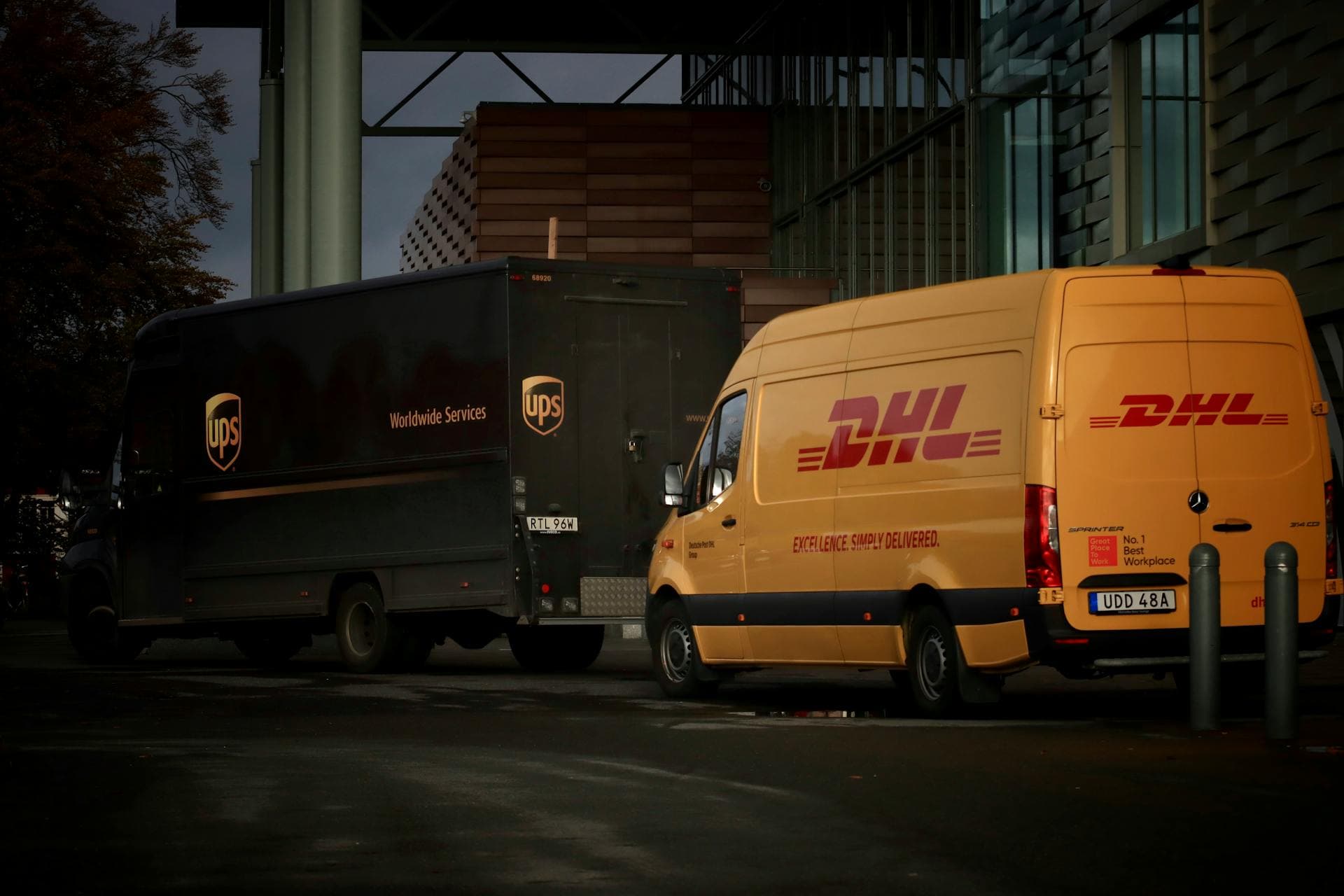 UPS and DHL delivery vans parked at night — Infinity Logistics multi-carrier parcel partners