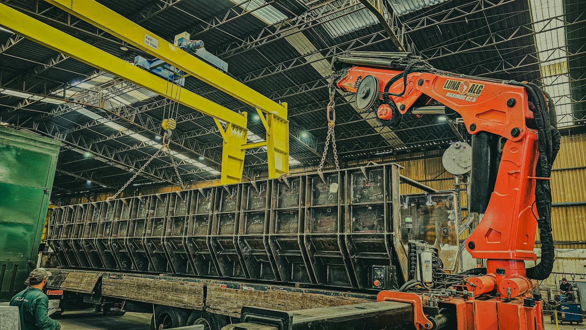 Heavy crane lifting steel in warehouse — Infinity Logistics project cargo operations