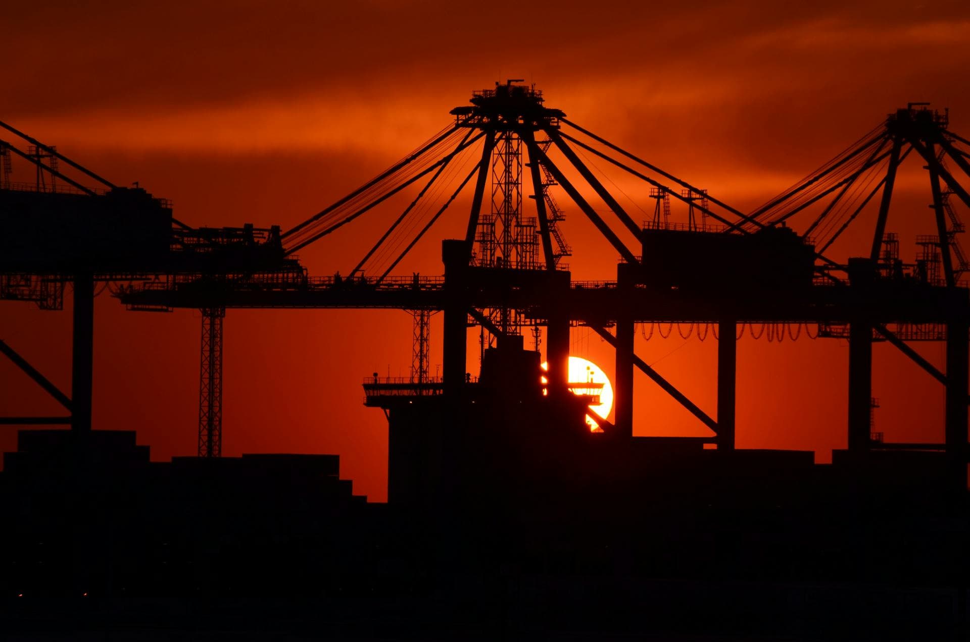 Port cranes silhouetted against dramatic sunset — Infinity Logistics freight forwarding